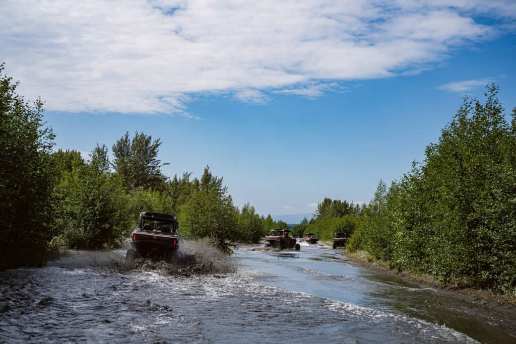 atvs wading through the river in the knik river valley