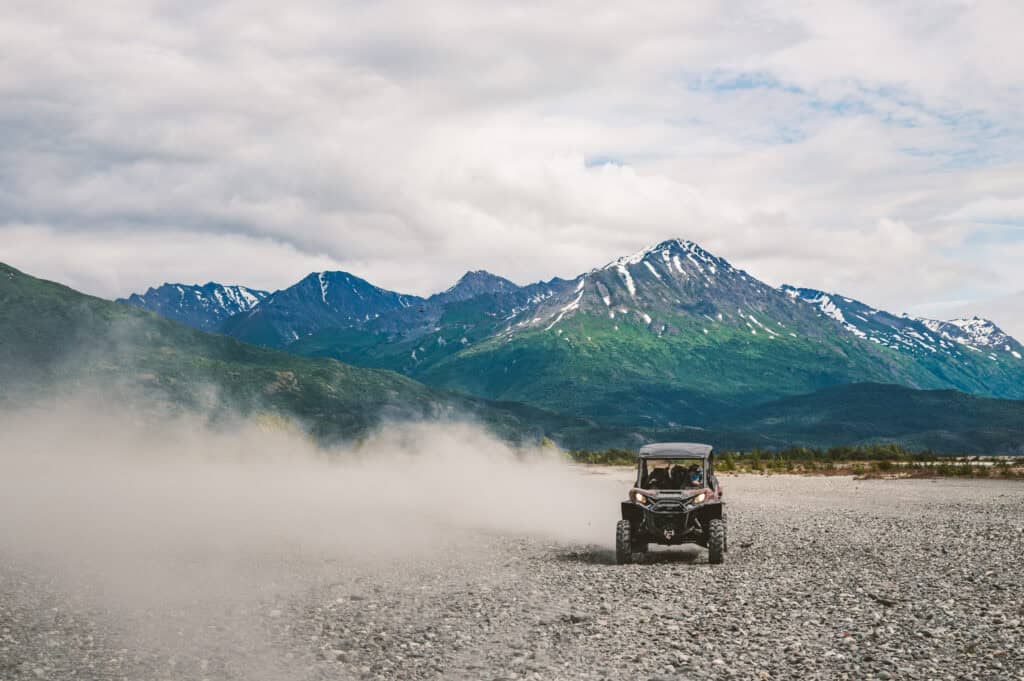 atv kicking up dust before the chugach mountains in alaska