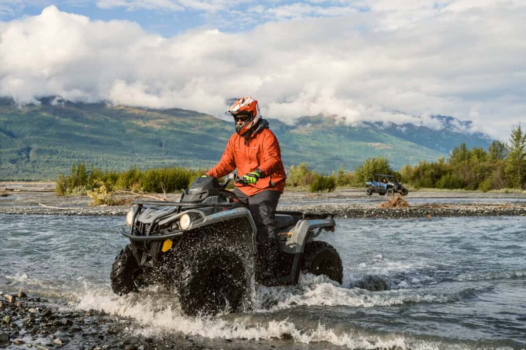 atv guide crossing a river in fall