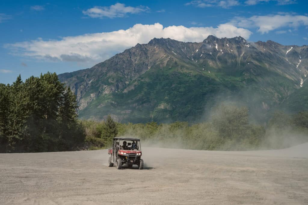 atv driving through dust with the chugach mountains in the background