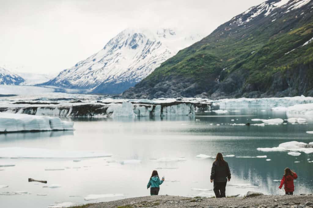 people standing before the knik glacier lake on a cloudy afternoon in alaska