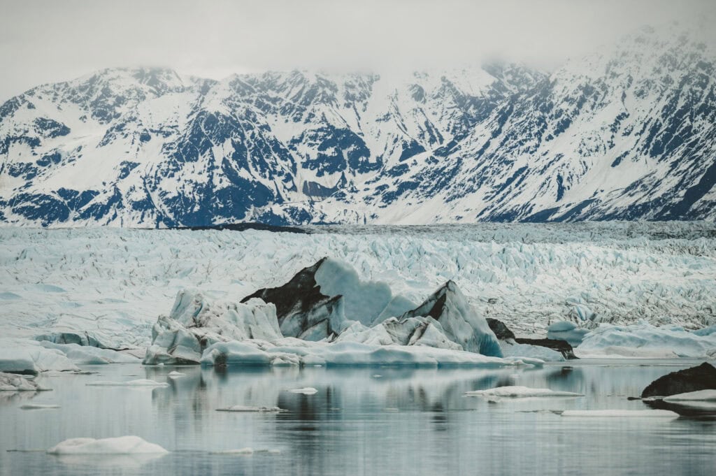 knik glacier lake and glacier before snowy mountains