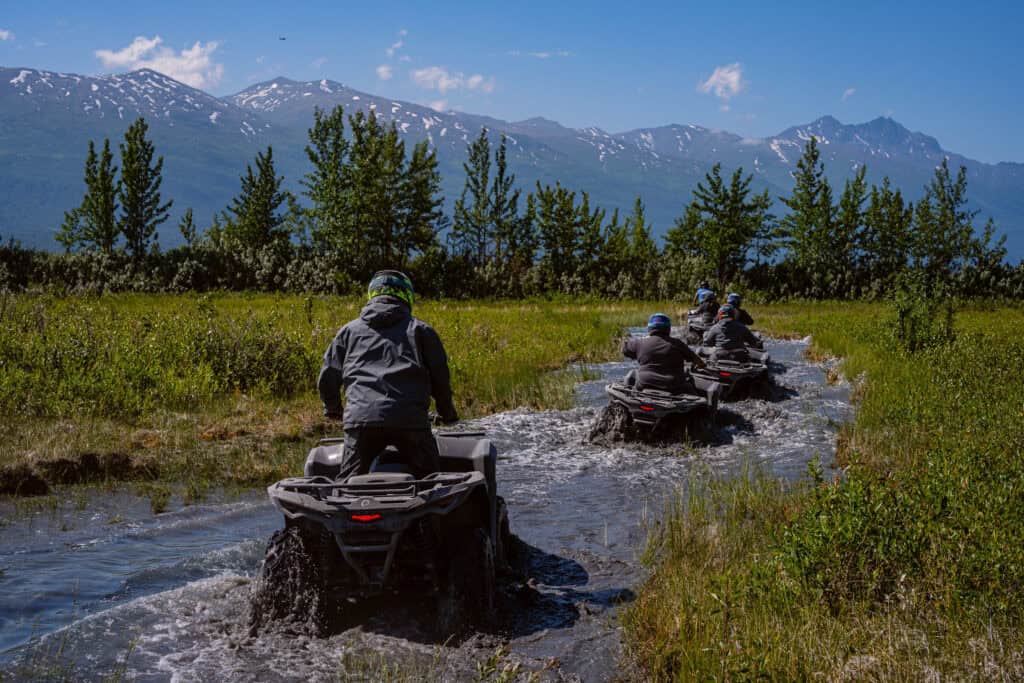 atvs driving through a creek in the backcountry near palmer alaska
