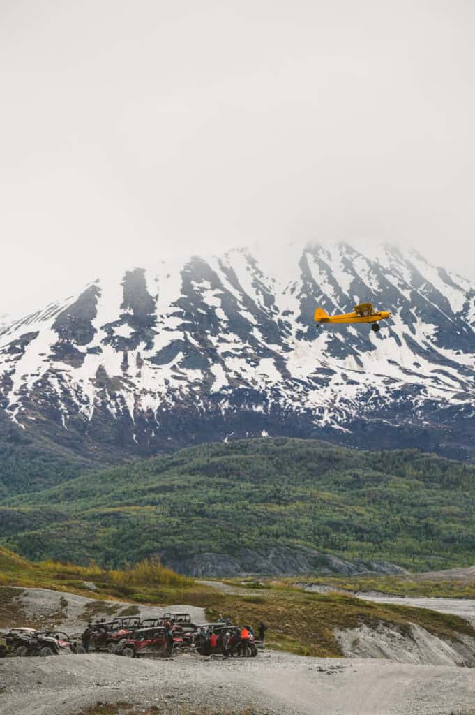 plane flying over a group of atvers in the knik valley outside of palmer alaska